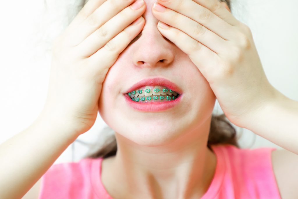 Teenage girl and closes the face with her hands.