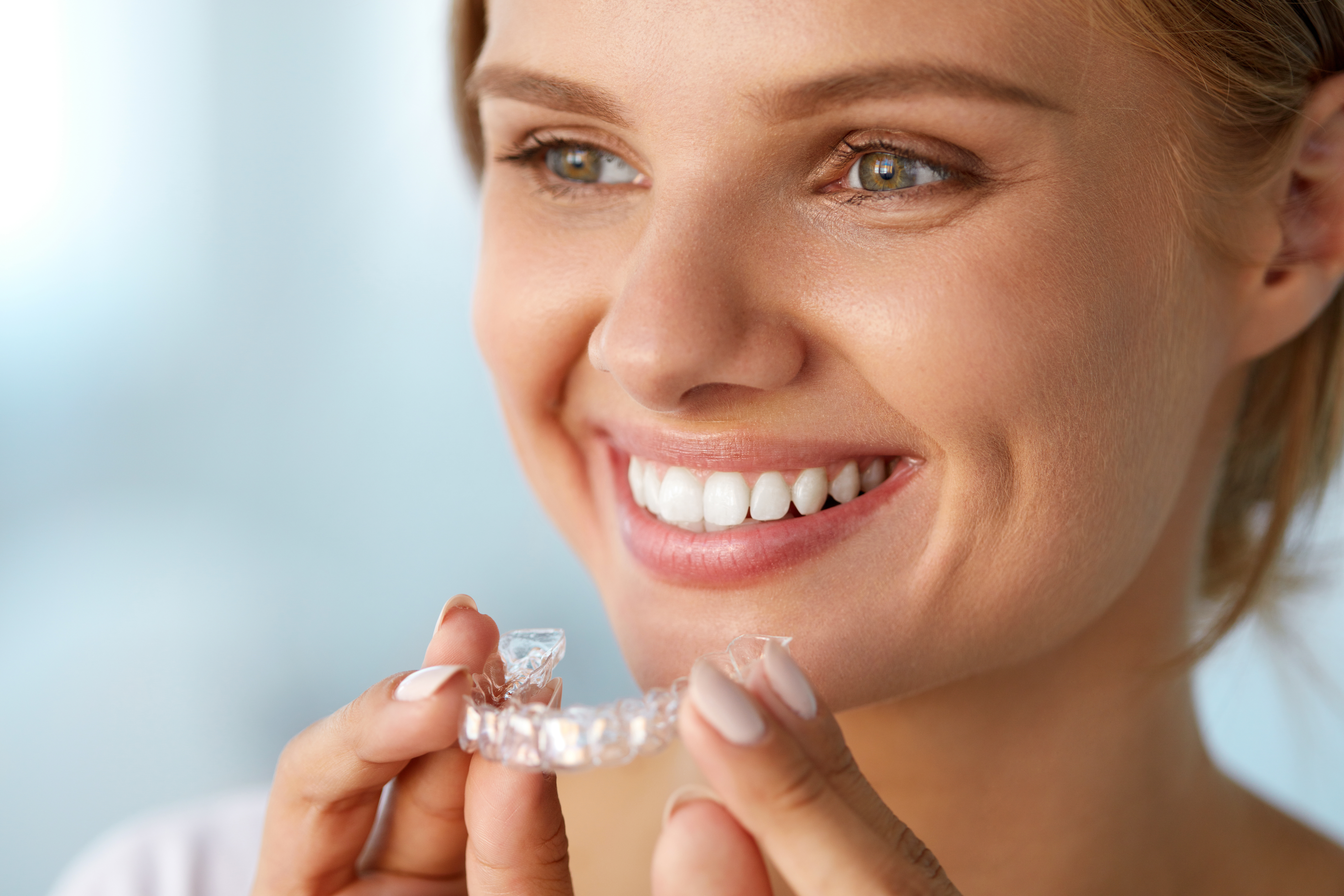 Portrait Of Smiling Woman With Healthy Straight White Teeth Holding Invisalign