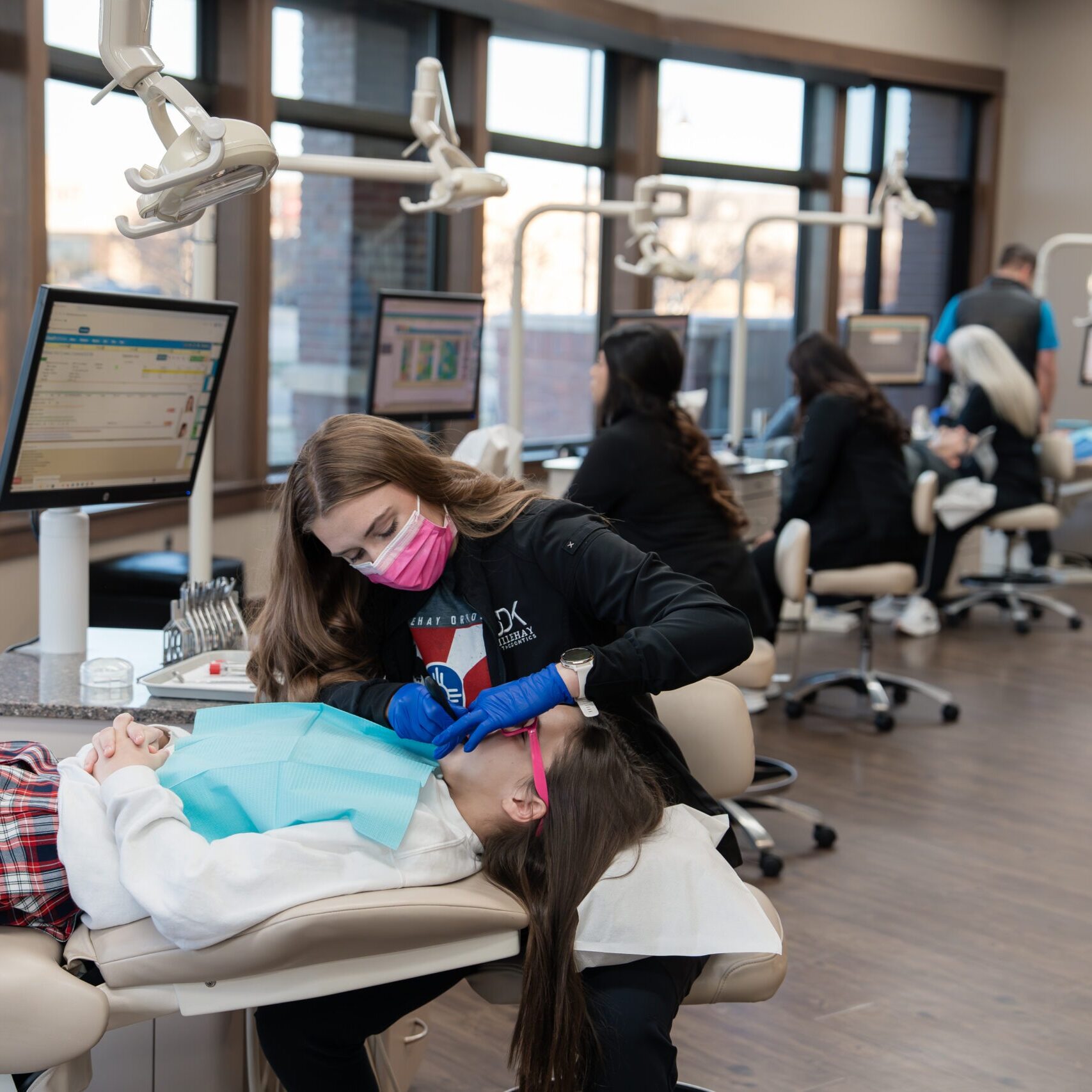 Dental assistant providing orthodontic care to a young patient in a modern clinic, featuring advanced equipment and attentive staff, representing Dillehay Orthodontics in Wichita.